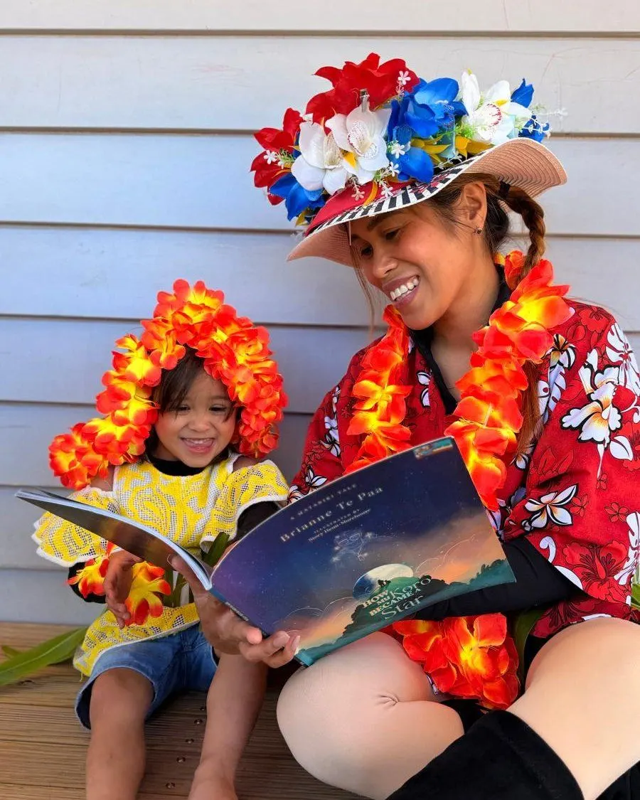 A teacher reading a Matariki story with a toddler, both dressed up in flowers